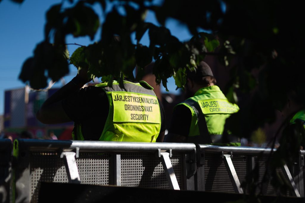 Valokuvaa, jossa kaksi järjestyksen valvojaa kääntyneenä selin kameraan.