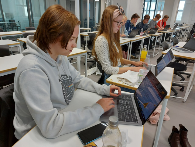 Valokuvassa kaksi nuorta istuu kannettavan tietokoneen äärellä.