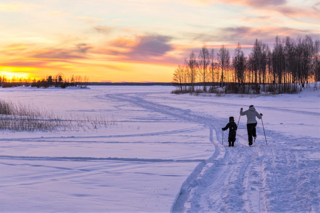 Valokuvassa aikuinen ja lapsi hiihtävä meren jäällä.