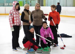 Valokuvassa kuusi ihmistä curling-kivien kanssa.