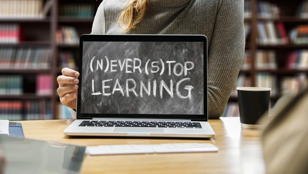 Valokuva, jossa pöydällä läppäri ja siinä teksti "Never stop learning".