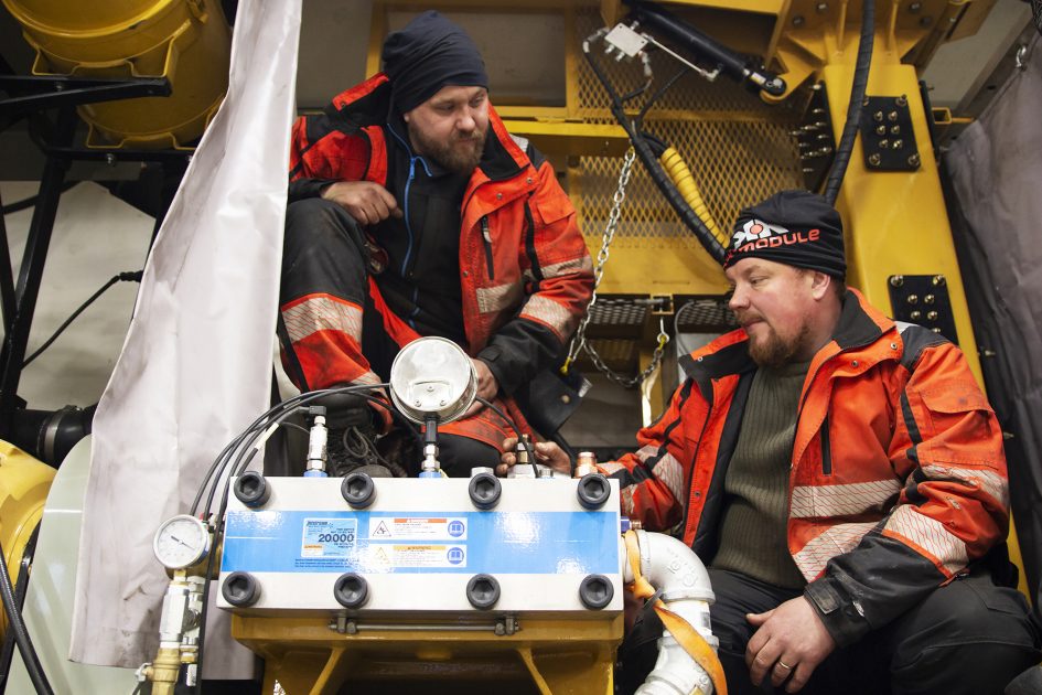 Valokuva, jossa kaksi miestä teknisen laitteen äärellä.