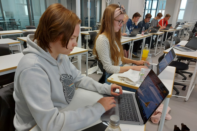 Valokuvassa kaksi nuorta istuu kannettavan tietokoneen äärellä.