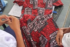 Photo of two students and a colourfull dress on the floor.